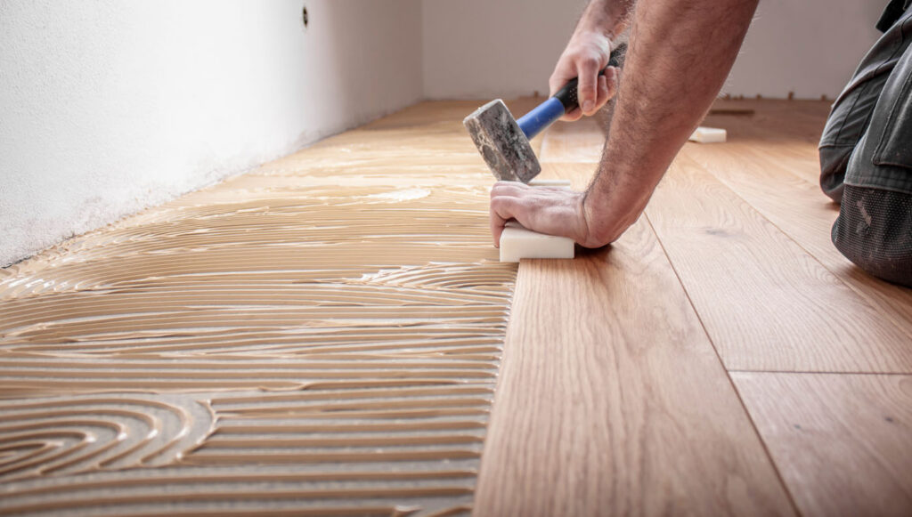 Handwerker verlegt Parkettboden